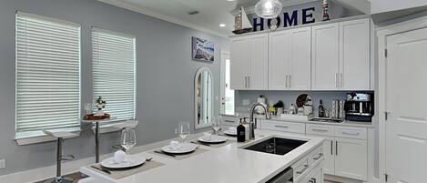 A modern kitchen with white cabinetry, a central island, and pendant lighting.