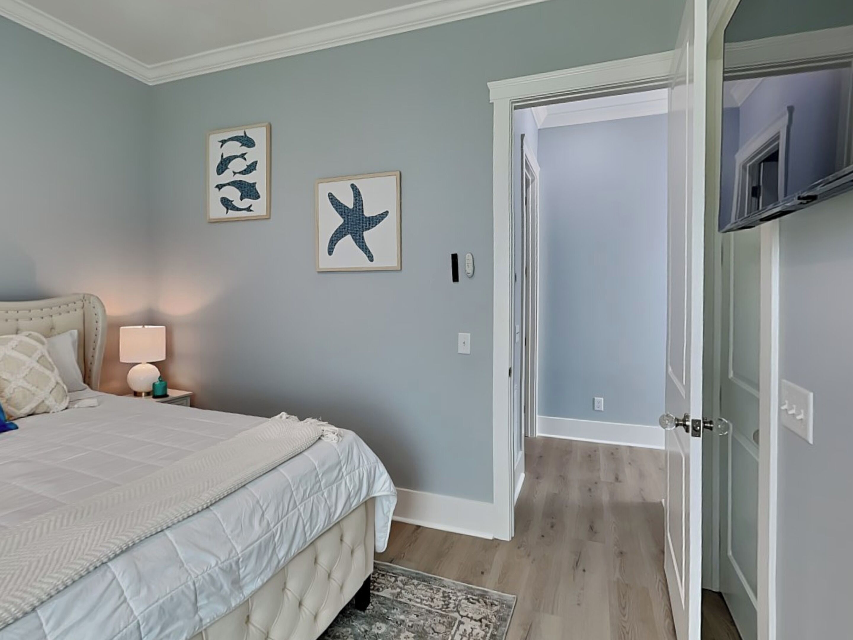 A bedroom with a bed, a nightstand, a lamp, and two framed pictures on the wall.