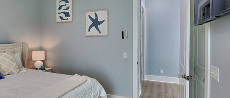 A bedroom with a bed, a nightstand, a lamp, and two framed pictures on the wall.