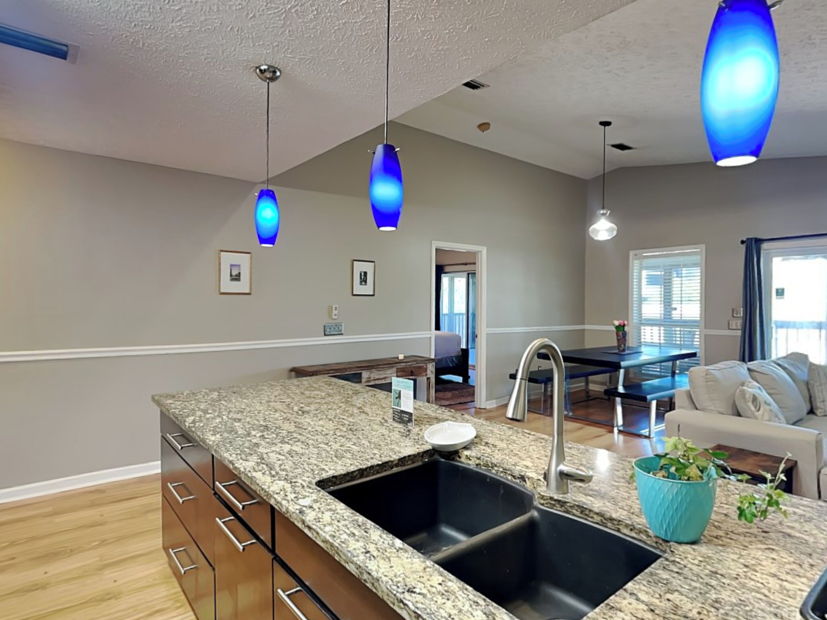 A modern kitchen with granite countertops, a double sink, and pendant lighting.