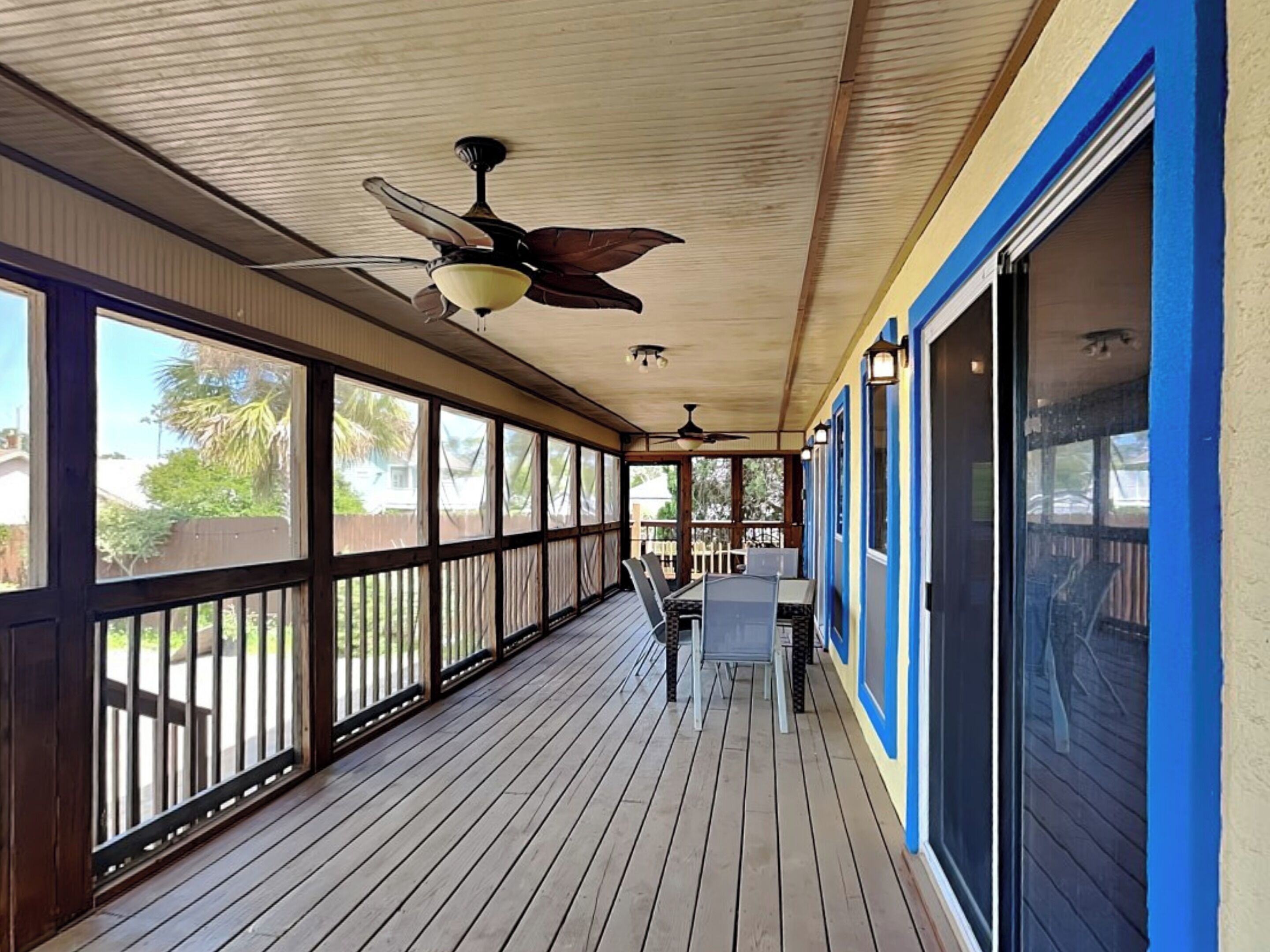 A covered porch with a ceiling fan, wooden railing, and a table with chairs.