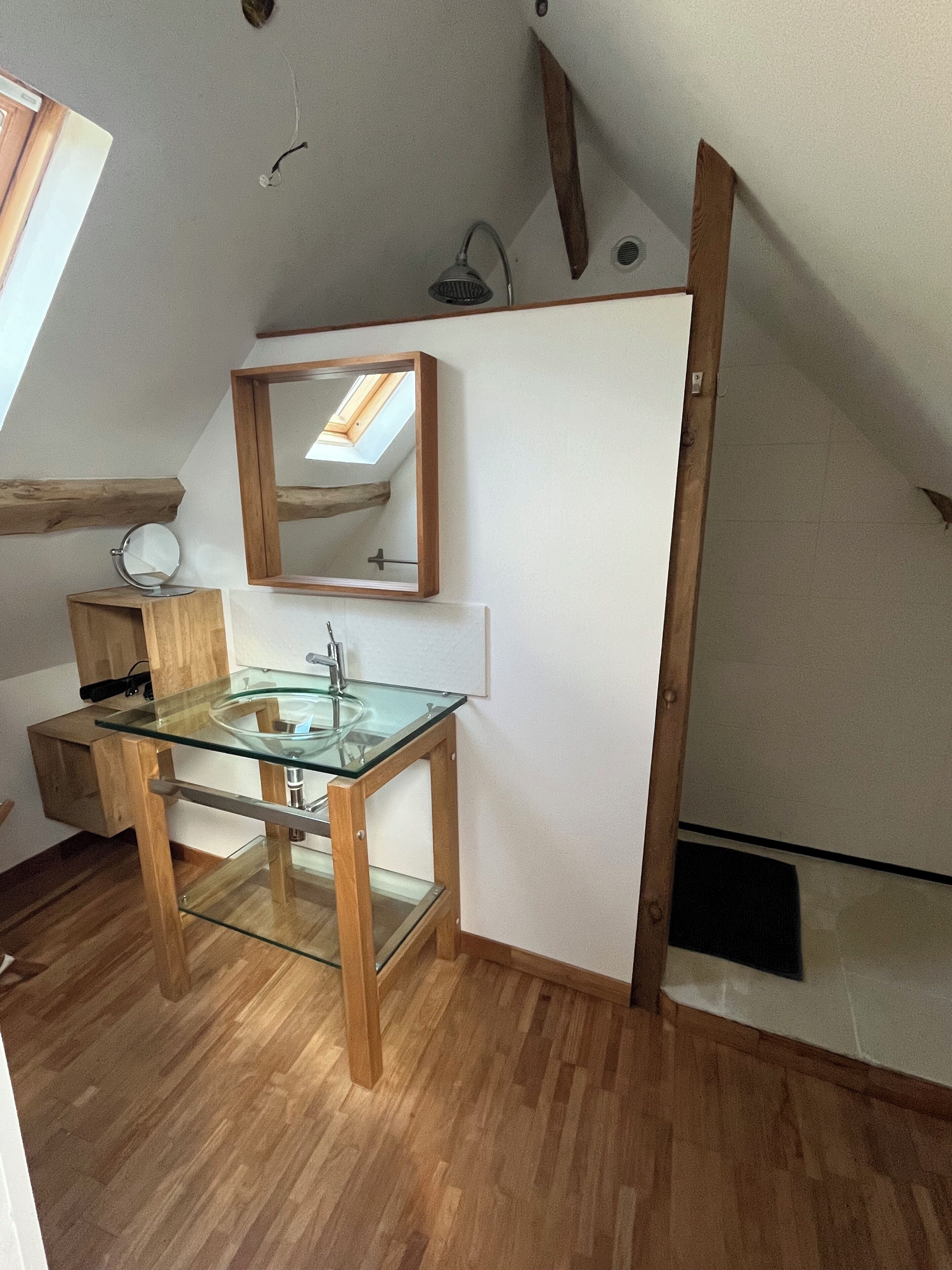 Ein modernes Badezimmer mit Oberlicht, Waschbecken aus Glas und Holzelementen.