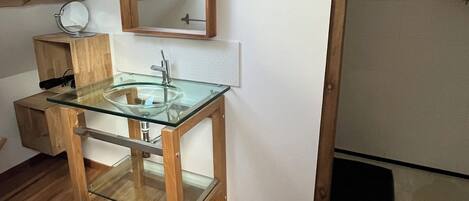 Ein modernes Badezimmer mit Oberlicht, Waschbecken aus Glas und Holzelementen.