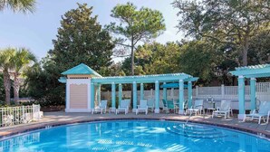 Une piscine avec des chaises longues et un kiosque.