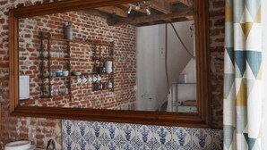 Un bagno con uno specchio grande, una parete in mattoni e uno schienale piastrellato.