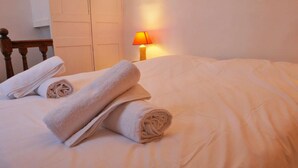 Un letto rifatto con asciugamani arrotolati e una lampada nell'angolo.