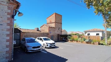 Un estacionamiento con dos coches, un edificio de ladrillo y un cielo azul despejado.