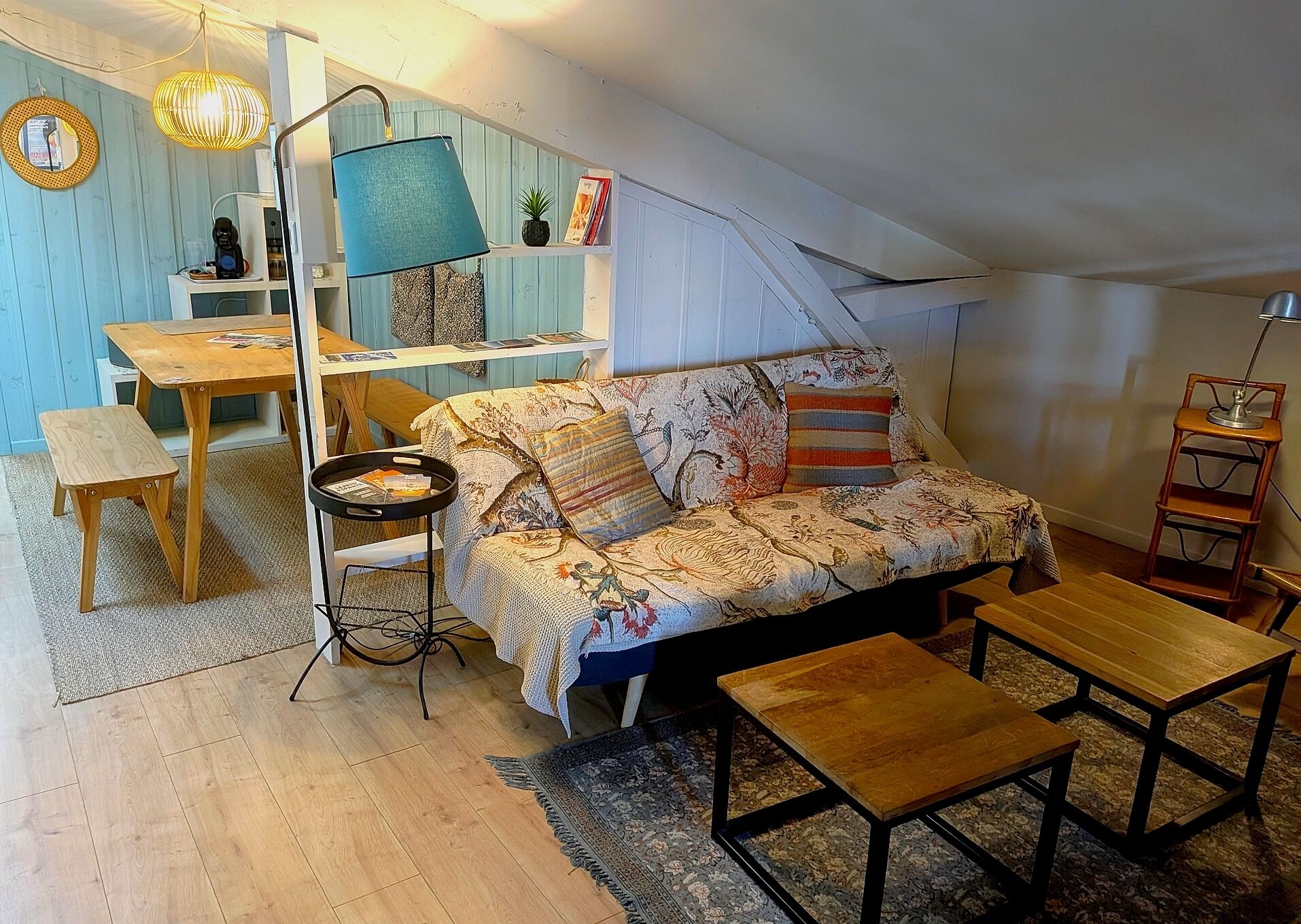 Een gezellig loft slaapkamer met een bank, een tafeltje, een vloerlamp en een boekenplank.