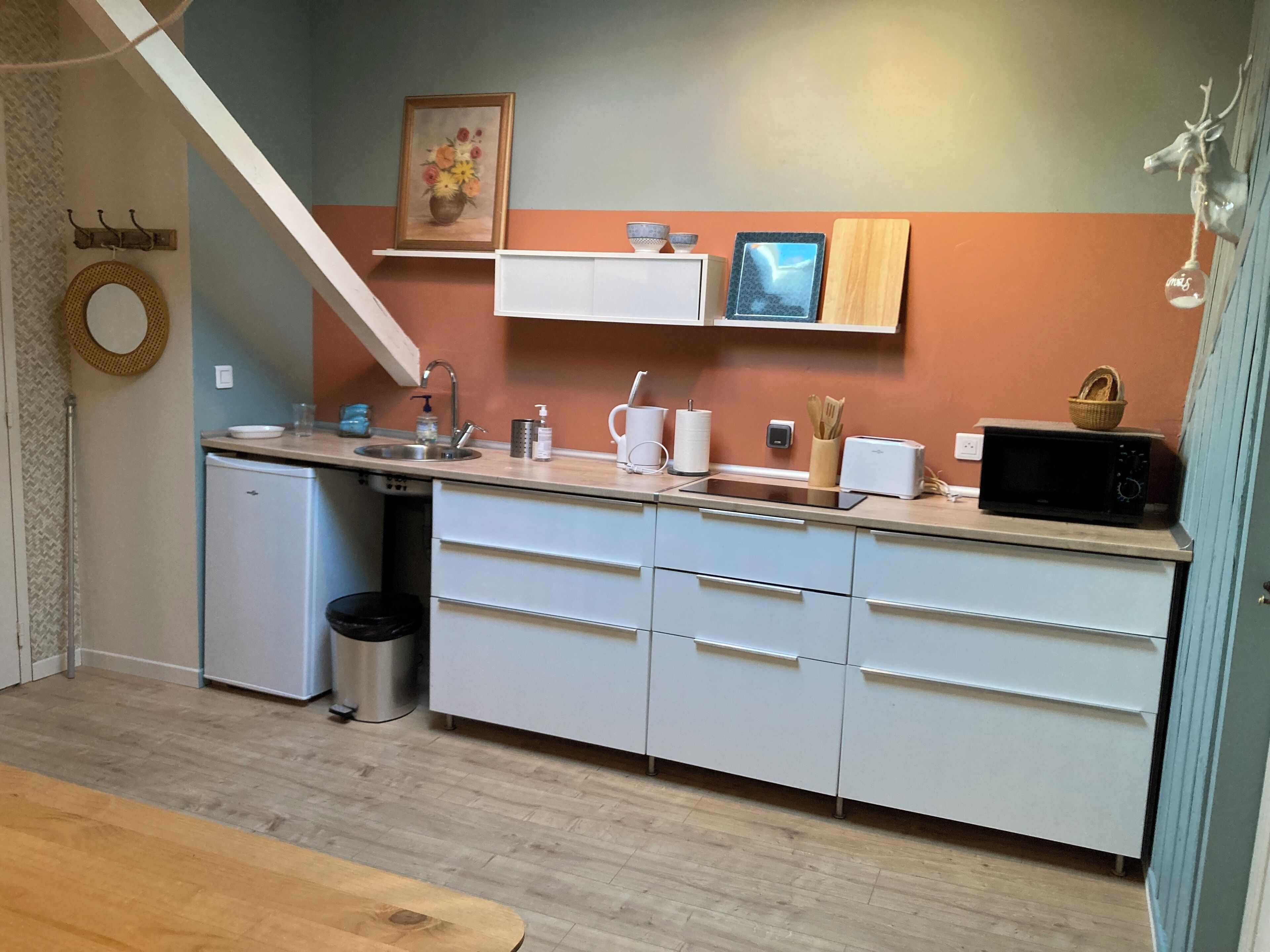 A compact kitchen with white cabinets, a sink, a microwave, and a small refrigerator.