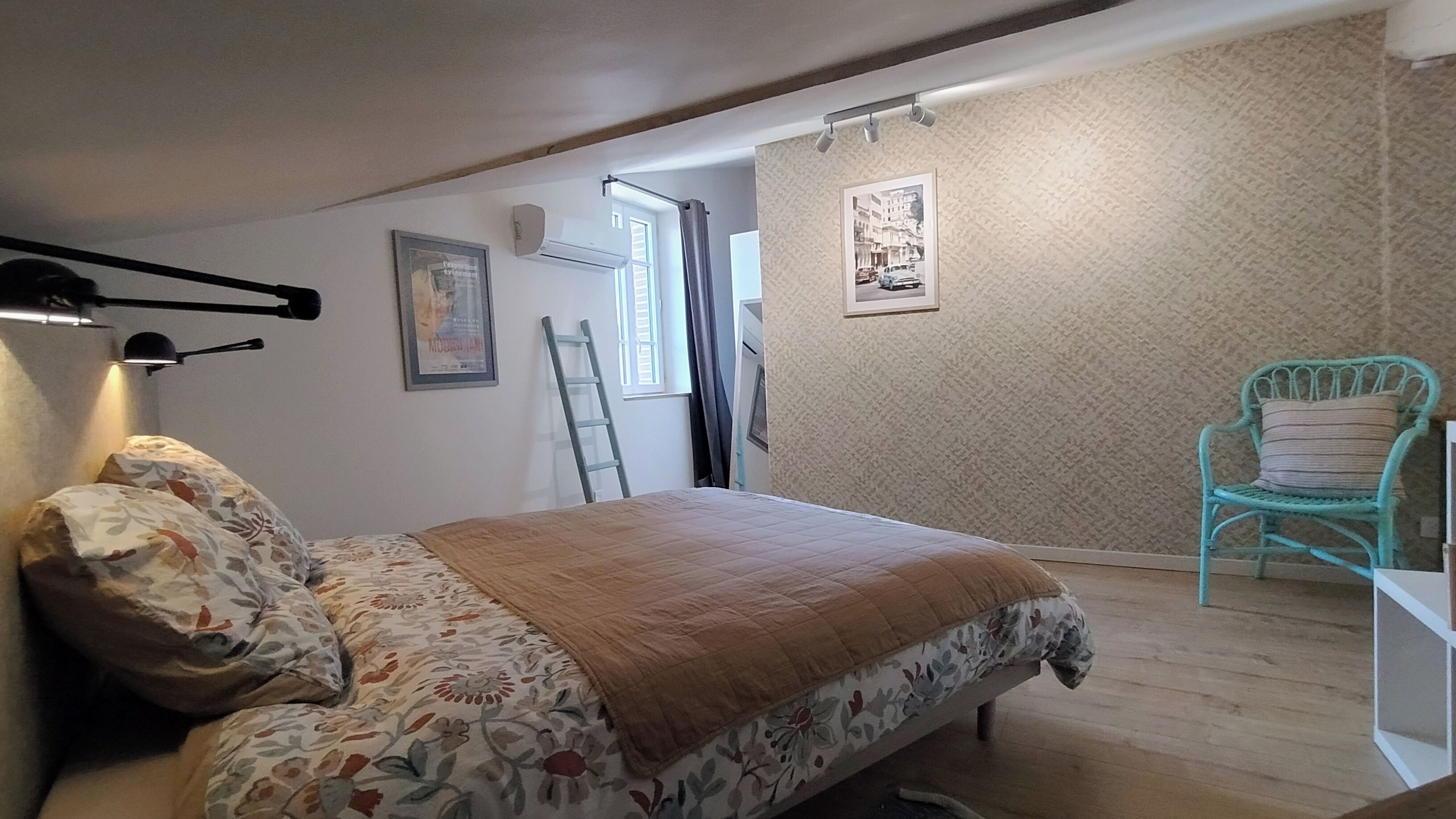 Een slaapkamer met een bed, een stoel, een ladder en een wandairconditioner.