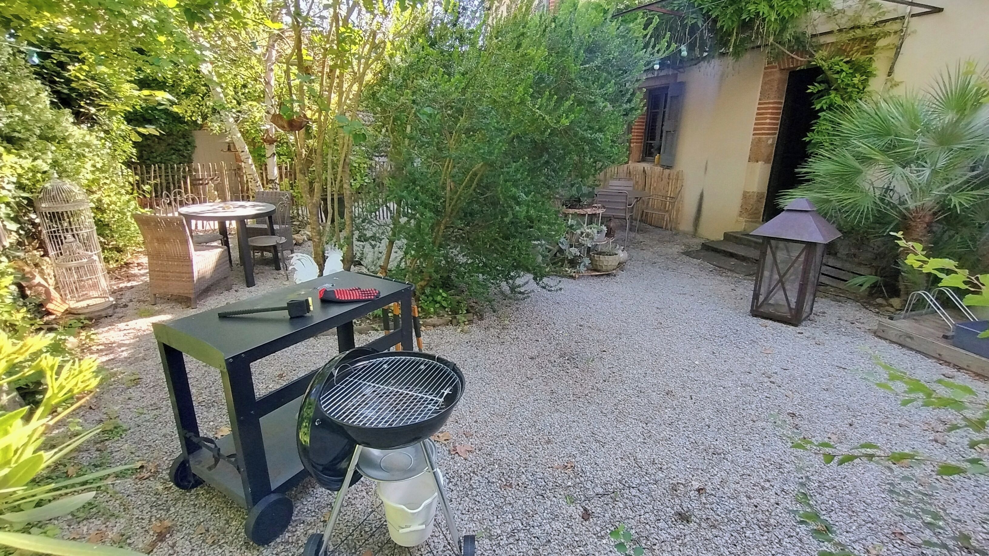 En terrasse med grill, udendørs møbler og et lille bord.