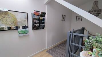Un couloir avec une carte, un présentoir de cartes postales et des tableaux encadrés accrochés au mur.