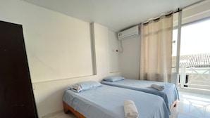 A hotel room with two beds, a TV, and an air conditioning unit.