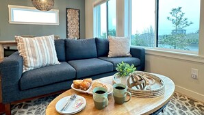 A cozy living room with a sofa, a coffee table, and a view of the outdoors. - After Dune Delight is a newly built waterfront escape with peaceful canal views—designed for slow mornings, cozy evenings, and effortless coastal living. (Ocean Shores)