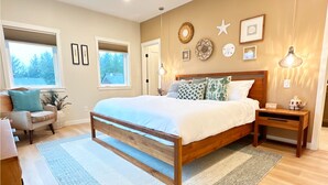 A bedroom with a large bed, bedside tables, a nightstand, a lamp, and a window with blinds. - After Dune Delight is a newly built waterfront escape with peaceful canal views—designed for slow mornings, cozy evenings, and effortless coastal living. (Ocean Shores)