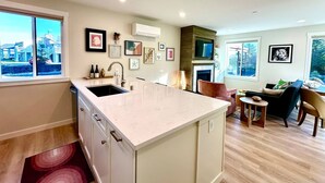 Een moderne keuken met een groot eiland, inbouwapparatuur en een eethoek met een open haard.