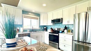 A modern kitchen with white cabinets, stainless steel appliances, and a marble countertop. - Waterfront Duplex w/Dock | Near Damon Point Beach (Ocean Shores)