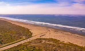A coastal landscape with a beach, ocean, and a road.