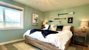A bedroom with a wooden bed, a large window, and nautical-themed decor.