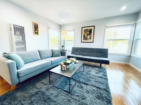 A modern living room with a grey sofa, a black sofa, a coffee table with decorative items, and a shaggy rug. - 804 SanMateo Comfortable 2BR Home/WiFI & Free Parking (San Mateo)