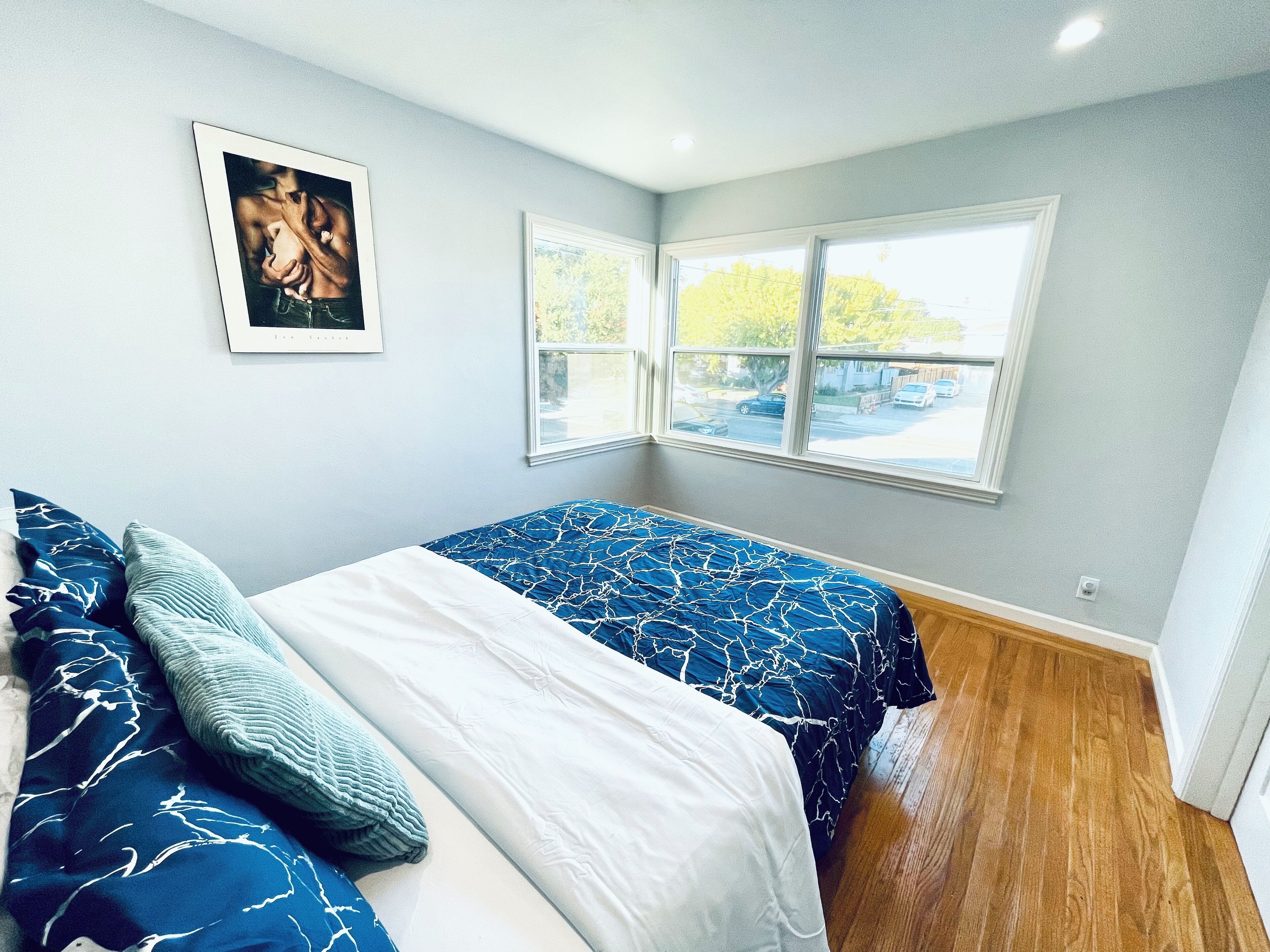 Een slaapkamer met een bed, een raam en een ingelijst kunstwerk aan de muur.