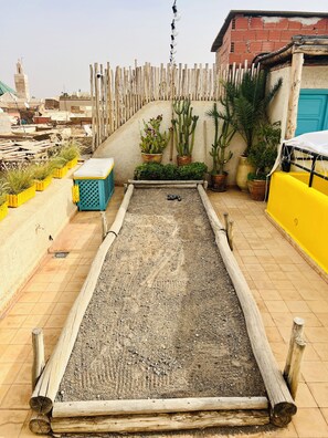 A rooftop garden with a wooden play area, potted plants, and a view of the cityscape. - Private medina riad - Swimming pool - Petanque & services (Marrakech)