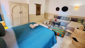 Un dormitorio con cama, sofá, una mesita y un adorno en la pared.