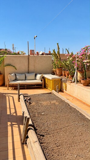 Una terrassa a la teulada amb zona de seients, plantes en testos i un petit jardí.