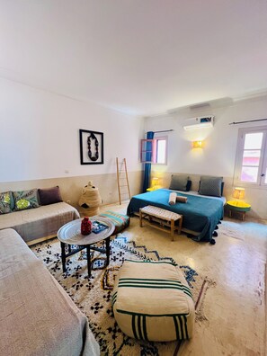 A cozy room with a bed, a sofa, a small table, and a bench. - Private medina riad - Swimming pool - Petanque & services (Marrakech)