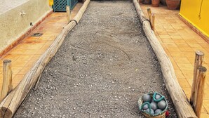 Un patio con una mesa de madera, plantas en macetas y una vista panorámica de la ciudad al fondo.