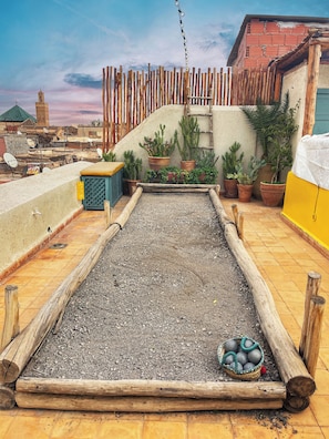 Une cour avec une table en bois, des plantes en pot et, en arrière-plan, une vue sur le paysage urbain.