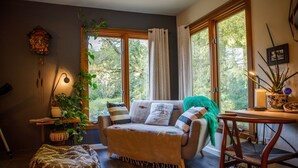 Un salon confortable avec un canapé, une petite table, une plante et une horloge au mur.