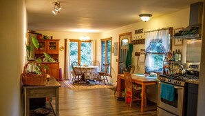 Une cuisine chaleureuse avec des meubles de rangement en bois, une table à manger avec des chaises et un poêle.