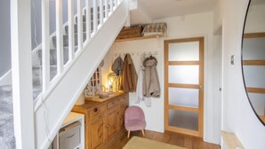 Un escalier menant à une chambre aménagée en mezzanine, avec une commode en bois, une chaise et un porte-manteau.