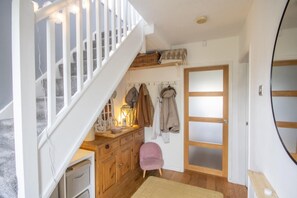 Staircase leads to an upper level, featuring a dresser, chair, and bench.