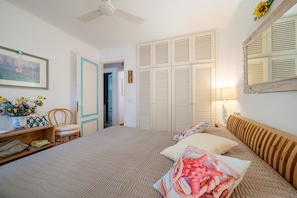 A bedroom with a bed, a chair, a desk, a lamp, and a wardrobe. - Casa Luis by Wonderful Italy (Olbia)