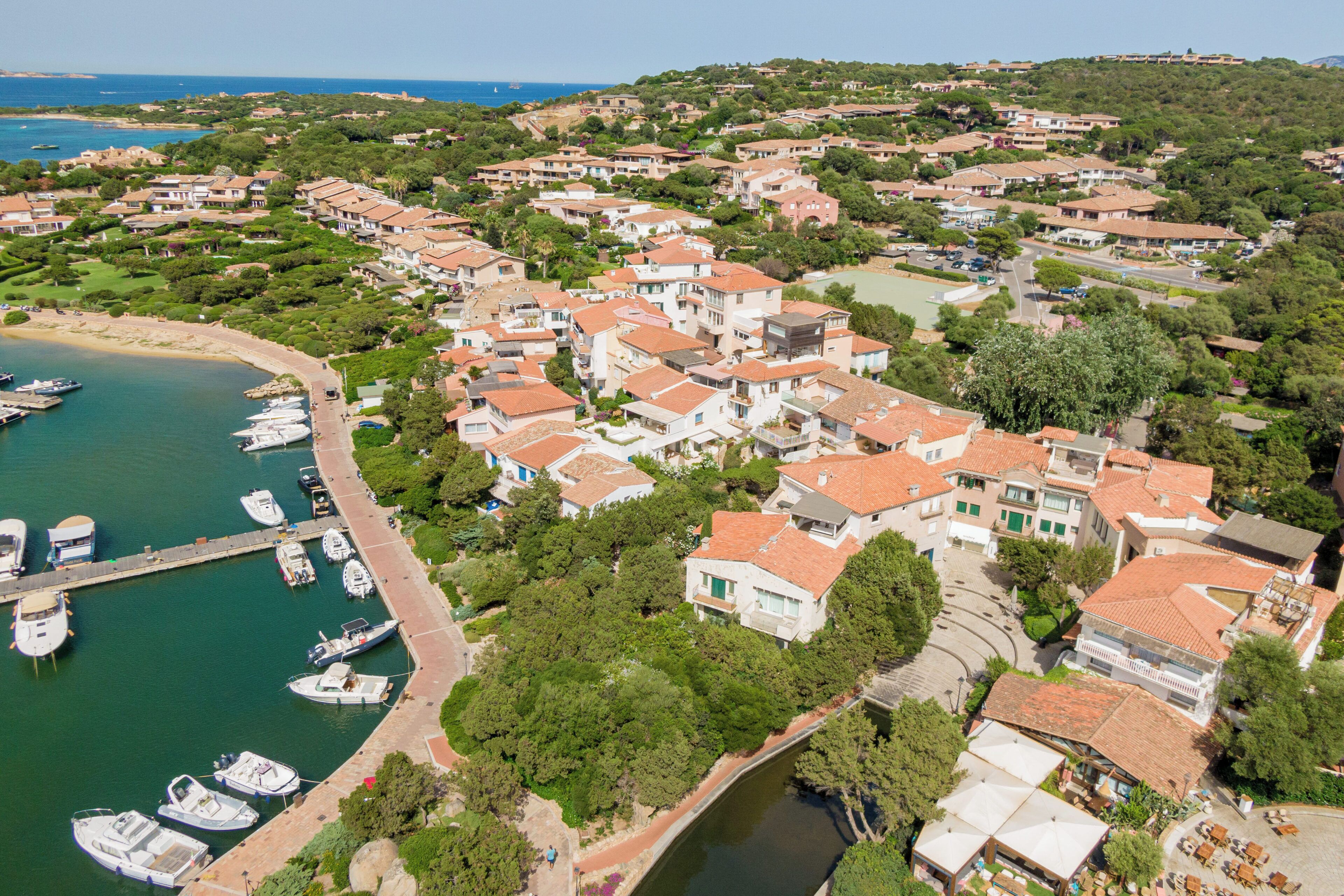 Vue aérienne d’une zone résidentielle côtière, avec des maisons, un port de plaisance et un petit pont.