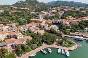 An aerial view of a coastal town with terraced houses, a marina with boats, and a central square. - Casa Luis by Wonderful Italy (Olbia)