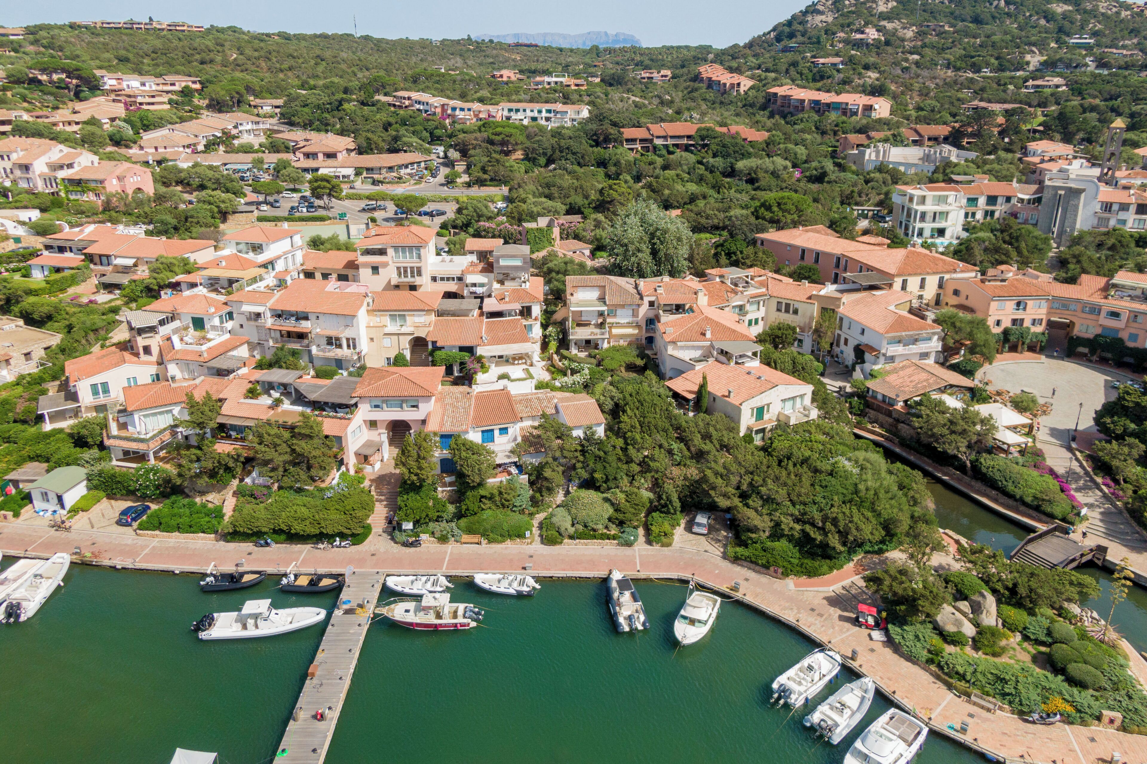 An aerial view of a coastal residential area with houses, a marina, and a dock.