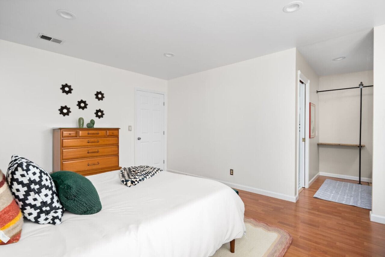 A bedroom with a bed, dresser, and wall decor.