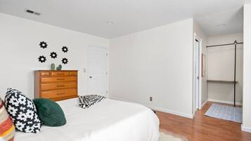 A bedroom with a bed, dresser, and wall decor.