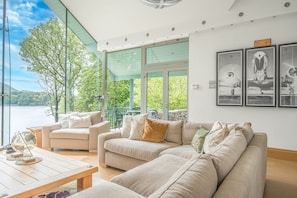 A spacious living area with a large window overlooking a lake, a sofa set, and a coffee table.