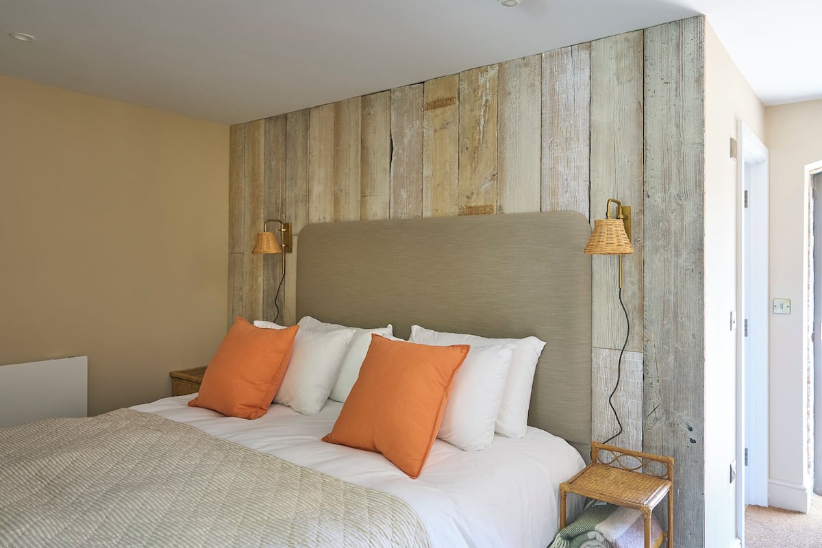 Un dormitorio con cabecera de madera, ropa de cama blanca y dos lámparas de noche.