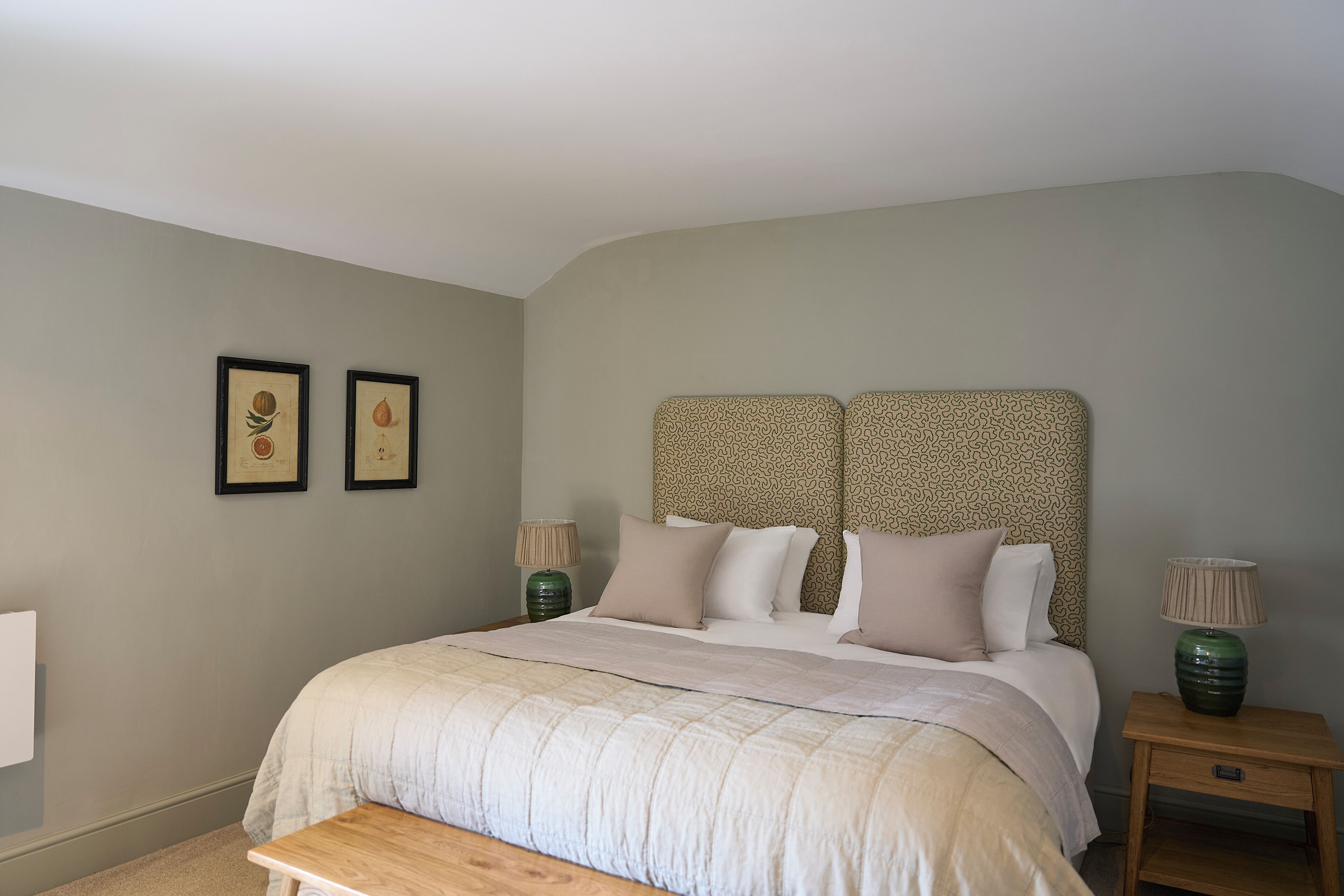 A bedroom with a large bed, two bedside tables, and a headboard with a patterned design.