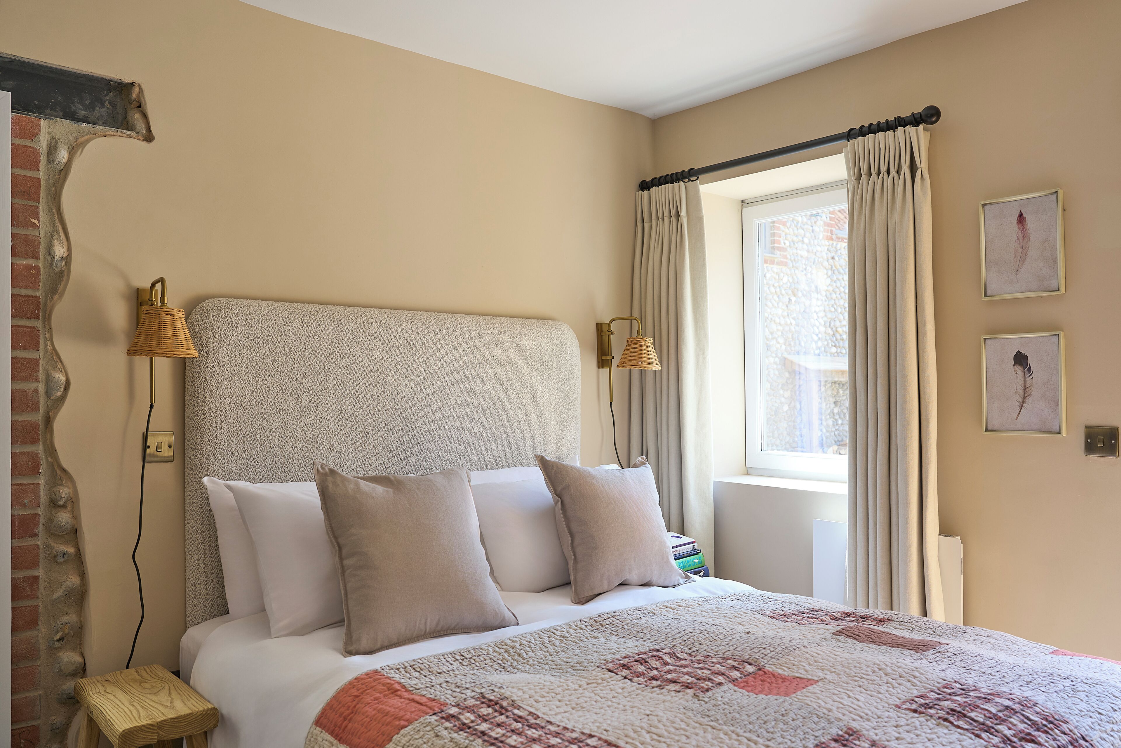 Un lit bien fait, avec une couverture à motifs, une tête de lit et deux lampes fixées au mur.