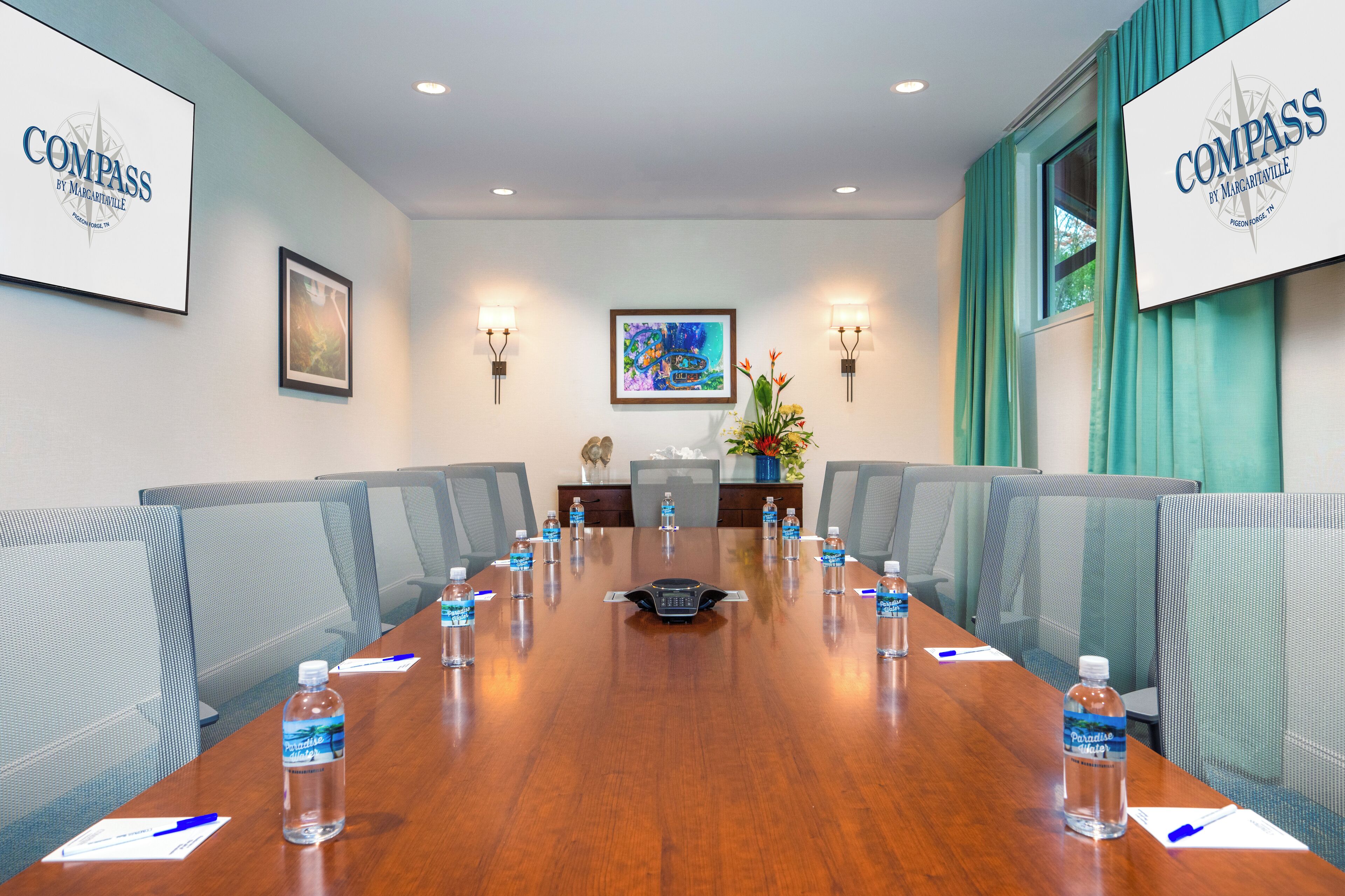 A conference room with a long table, chairs, water bottles, and name cards.