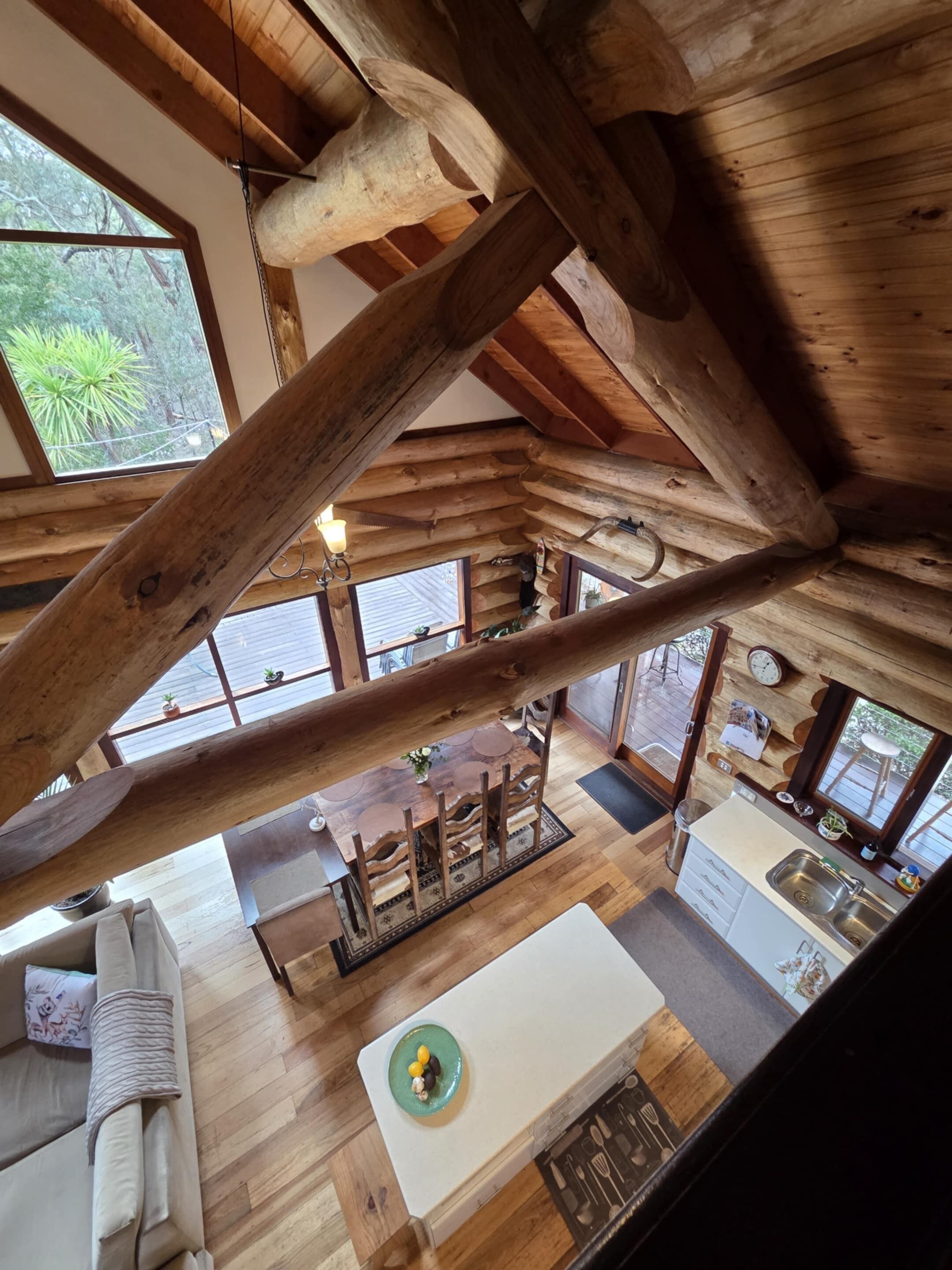 Un ampio loft con travi a vista in legno, una zona pranzo centrale e una cucina con una grande finestra.