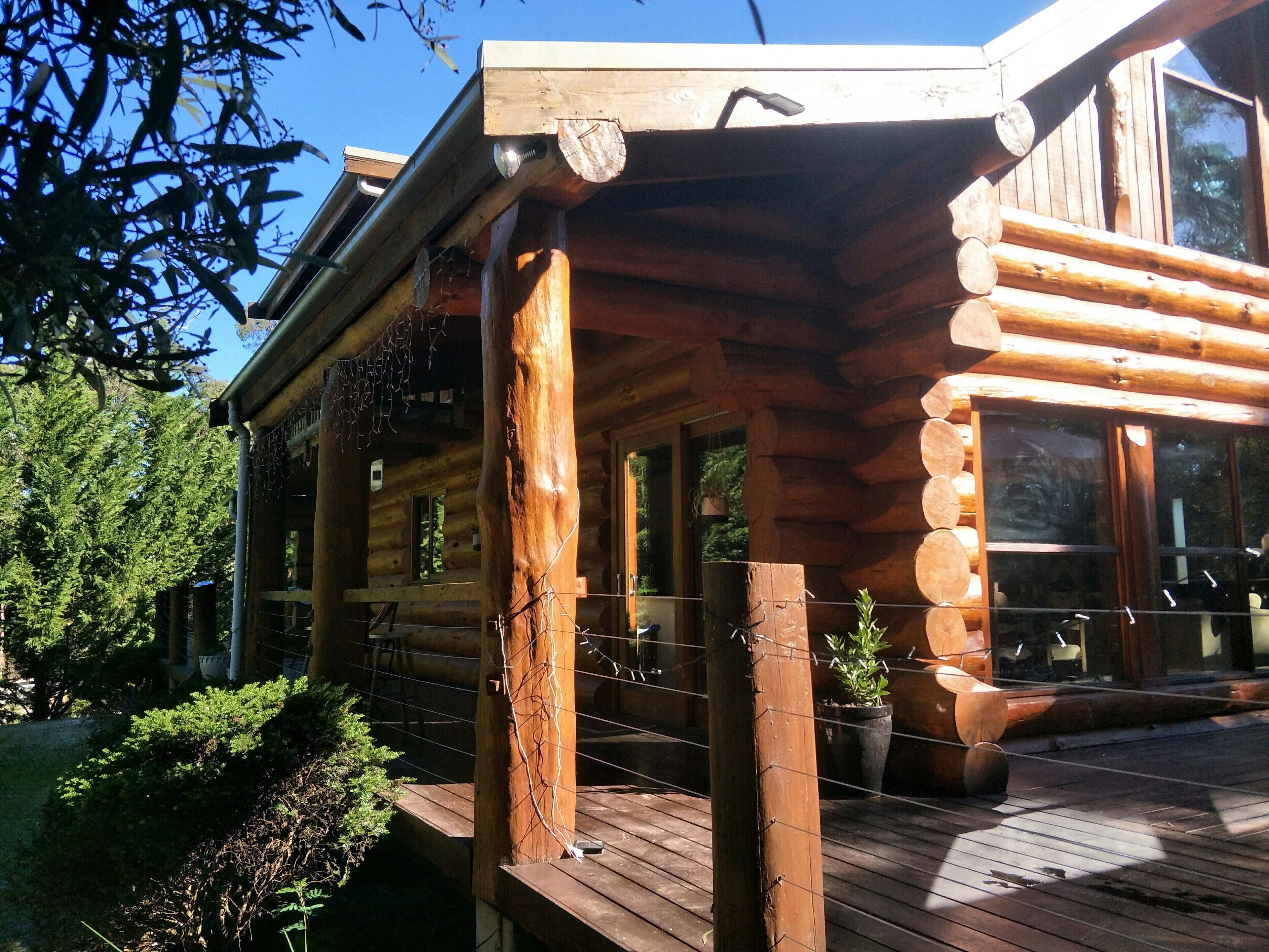 A wooden cabin with a wooden deck, large windows, and a porch area.