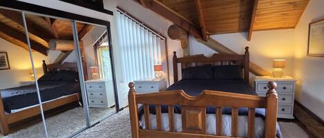 Un dormitorio con techo de madera, una cama grande, un espejo y una ventana con persianas.