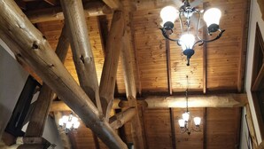 Ein Blockhaussinnere mit freiliegenden Holzbalken, einer Holzbodenverkleidung und einer Kristallleuchter.